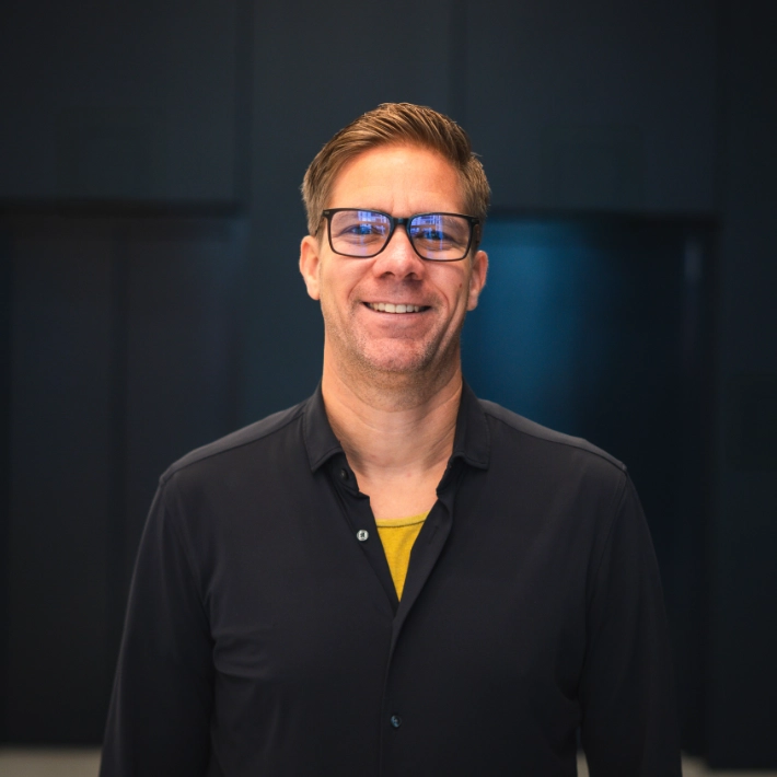 Portrait von Mann mit Brille und schwarzem Oberteil.