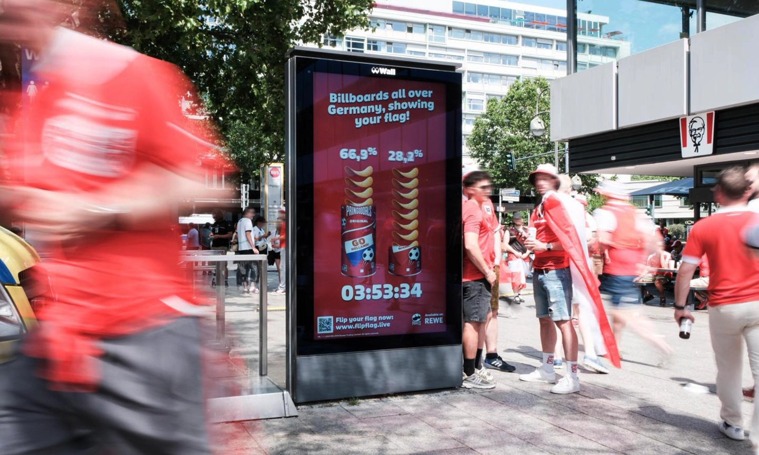 City Light Poster mit Chips Werbung zur EM Zeit mit Fußballfans in berliner Fußgängerzone