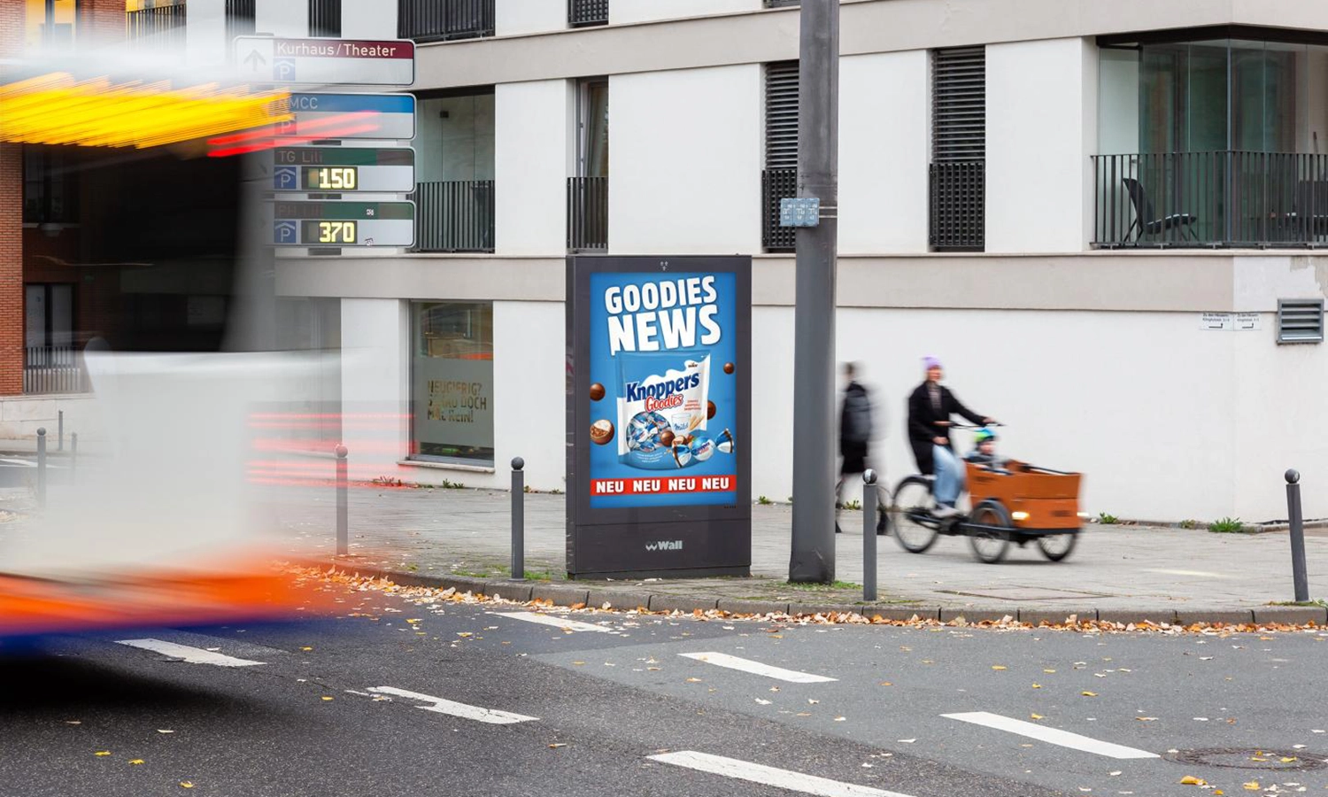 City Light Poster mit Süßwarenwerbung an einer belebten Straße in Wiesbaden.