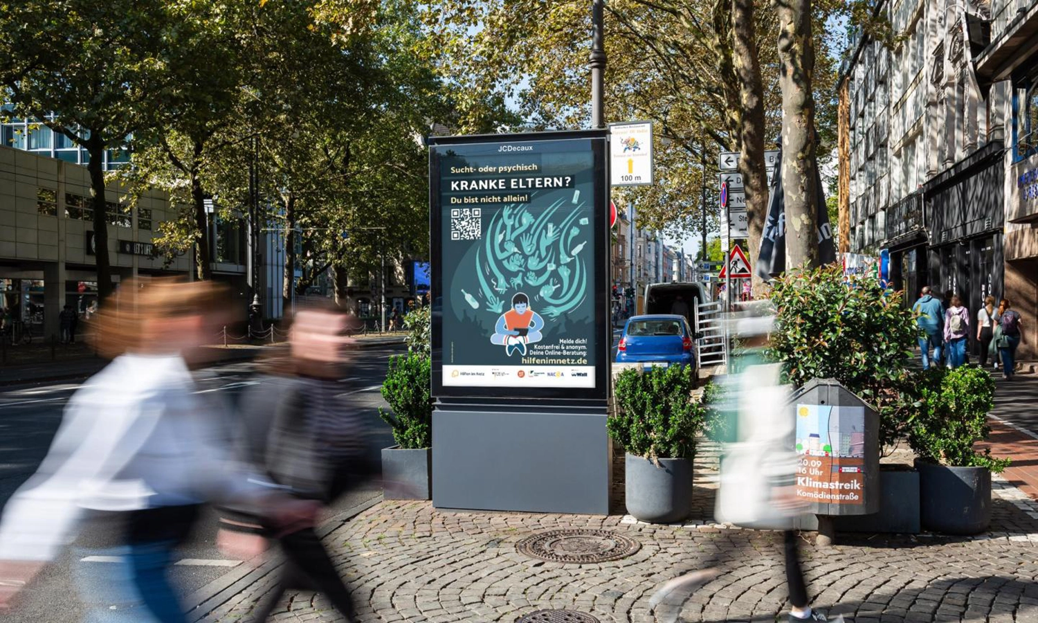 City Light Poster mit Suchthilfewerbung in Kölner Innenstadt an einer Straße.