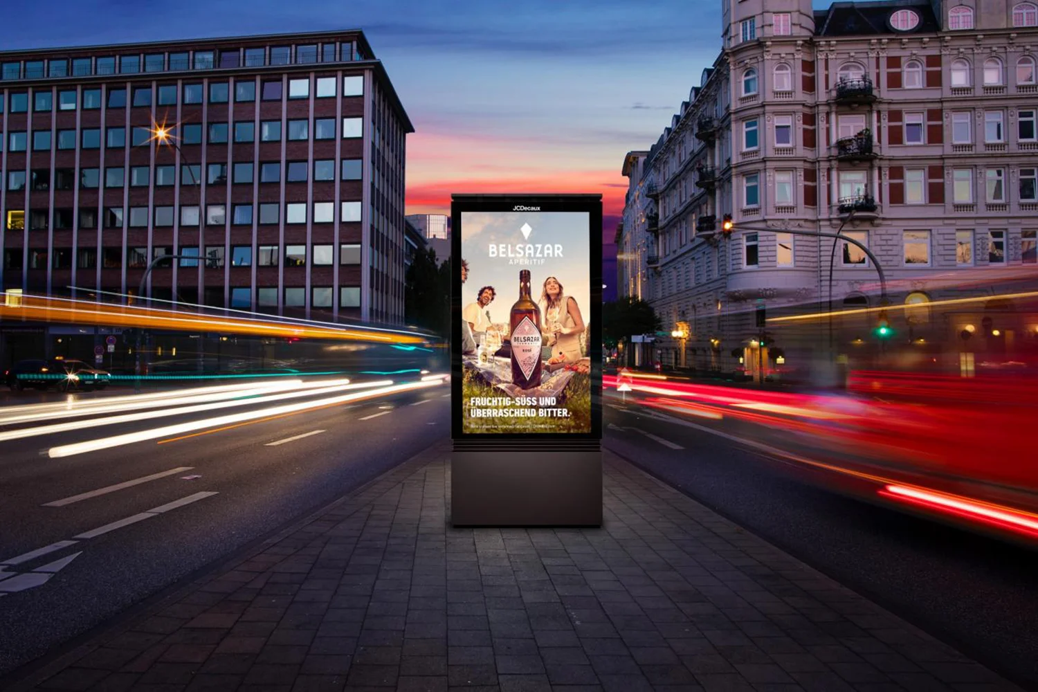 Digital City Light Poster zeigt Werbung für alkoholisches Getränk an starkbefahrener Straße zur Dämmerung.