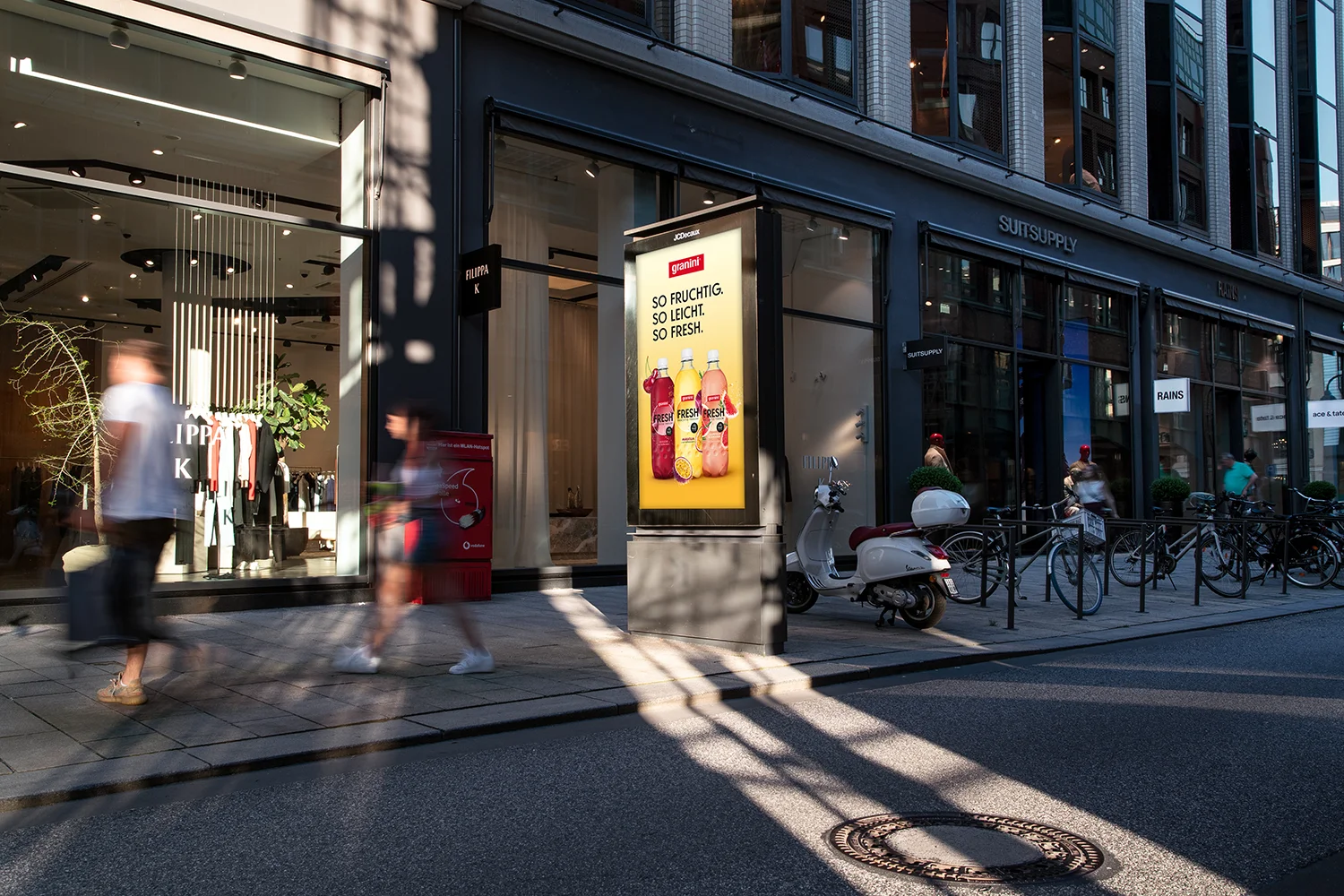 Digital City Light Poster zeigt Getränkewerbung in Einkaufsstraße im Sommer.