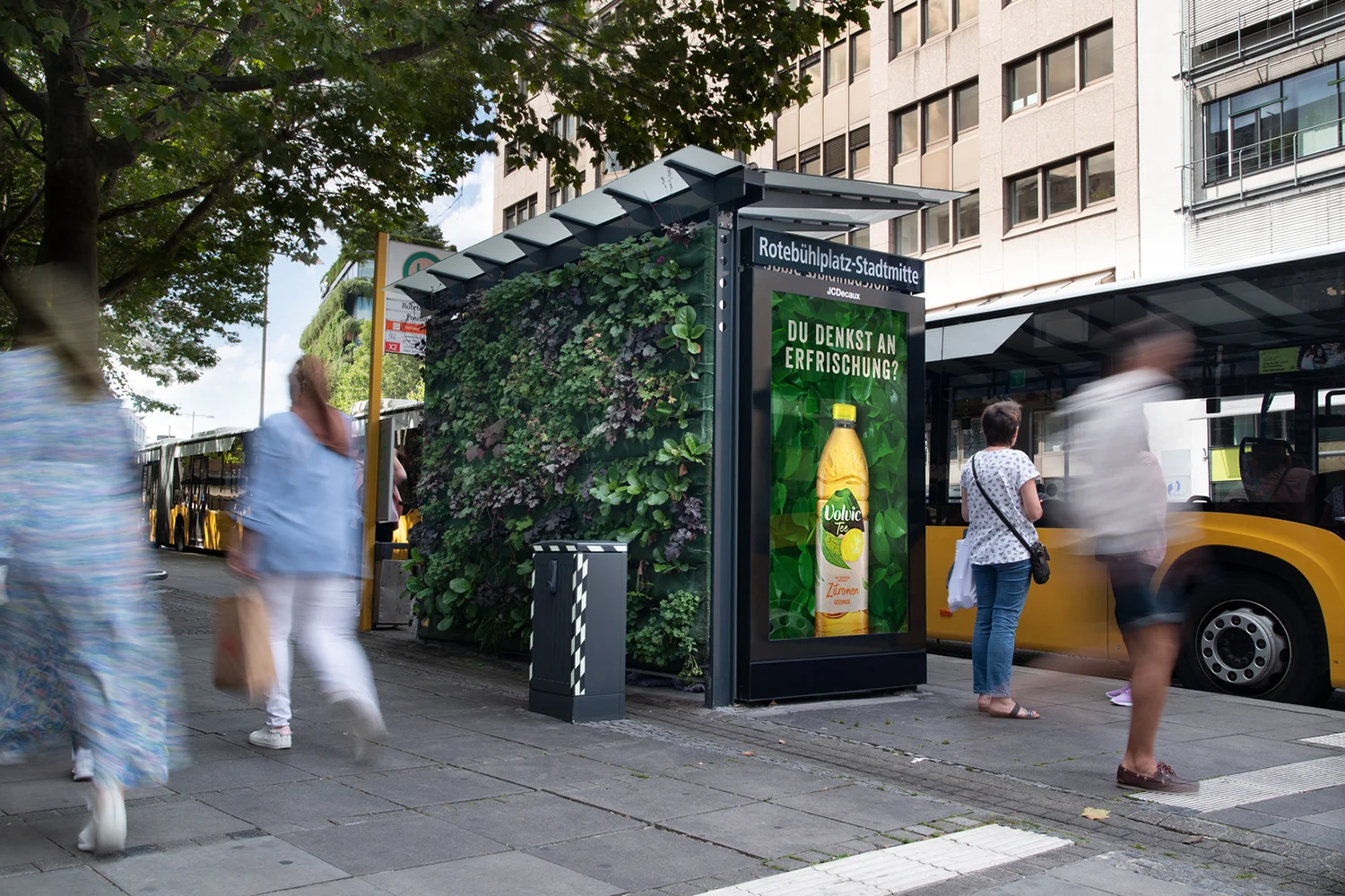 Digital City Light Poster in Bus-Wartehalle mit Grünwand zeigt Getränkewerbung am Rote Bühl Platz in Stuttgart.