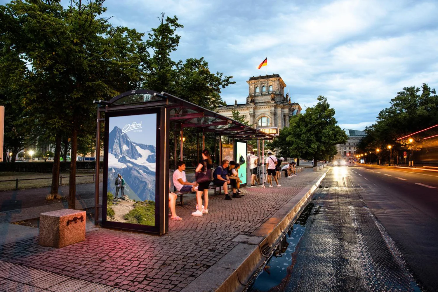 Digital City Light Poster mit Tourismus-Werbung an Buswartehalle im Regierungsviertel Berlins.