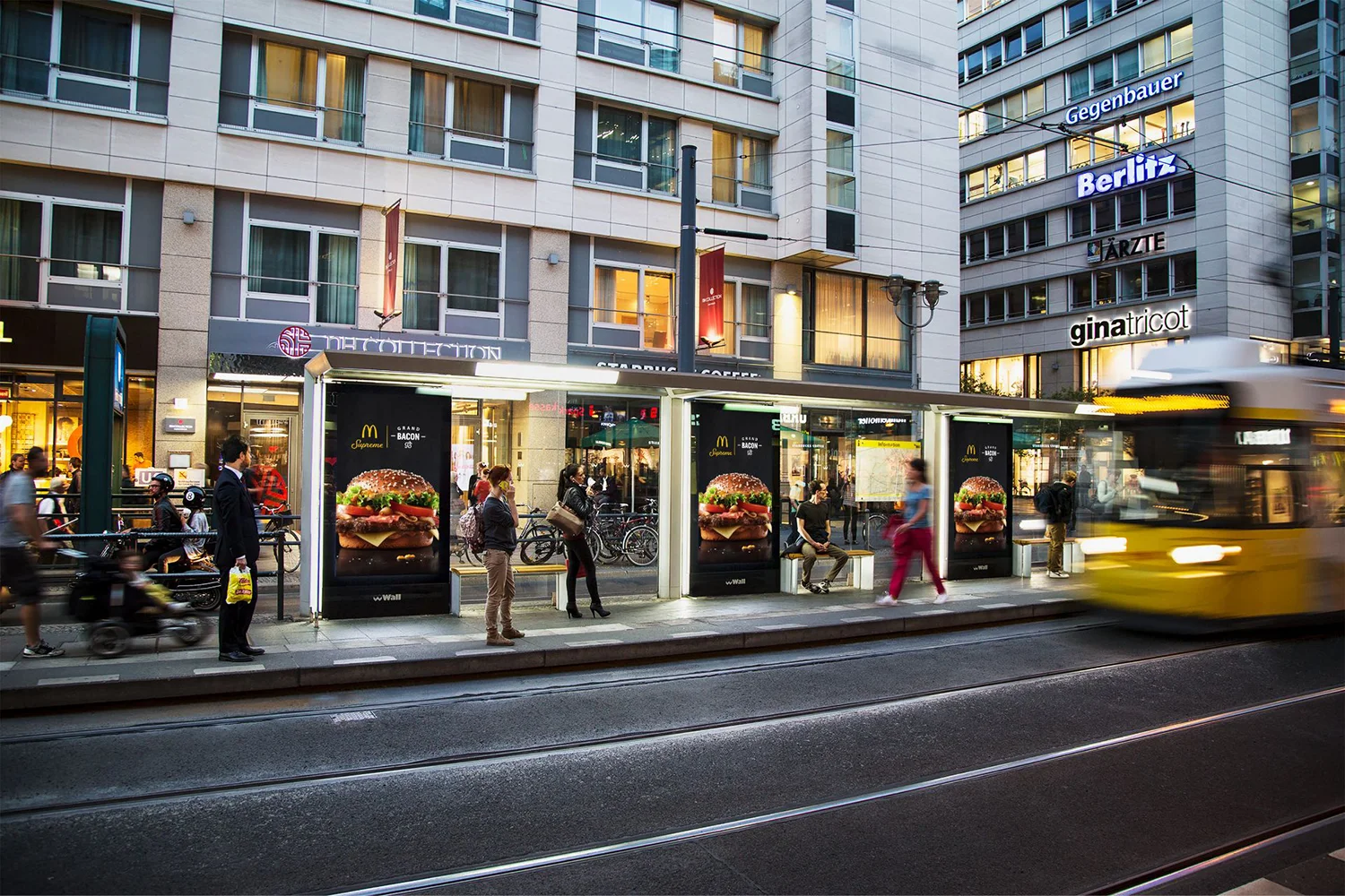Drei Digital City Light Poster an Tram-Wartehalle in der Berliner Friedrichstraße zeigen Werbung einer Fast Food-Kette.