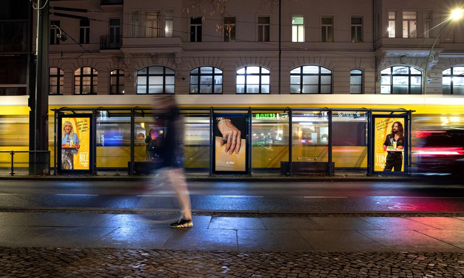 Drei Digital City Light Poster mit Fastfoodwerbung in Trammwartehalle, leuchten in bunten Farben  in der Oranienburgerstraße in Berlin