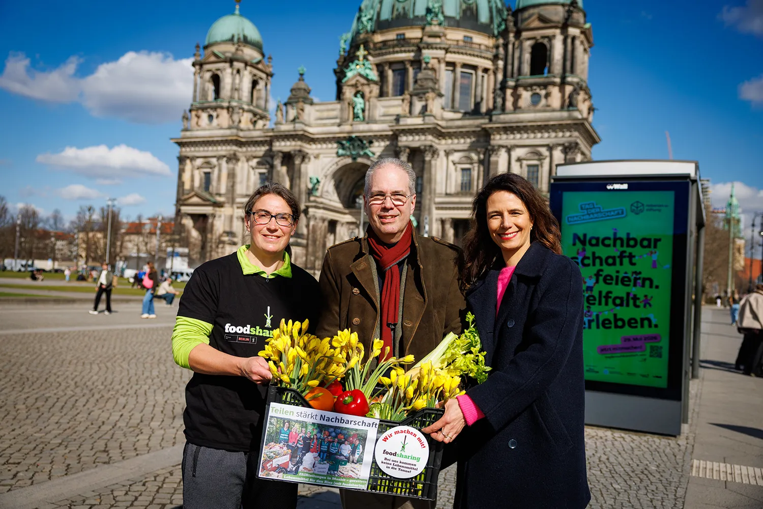 Katharina Mölter, Gründerin foodsharing Moabit, Patrick Möller, Geschäftsführer Wall, und Katharina Roth, Geschäftsführerin der nebenan.de Stiftung feiern die Enthüllung der Kampagne zum Tag der Nachbarschaft 2026.