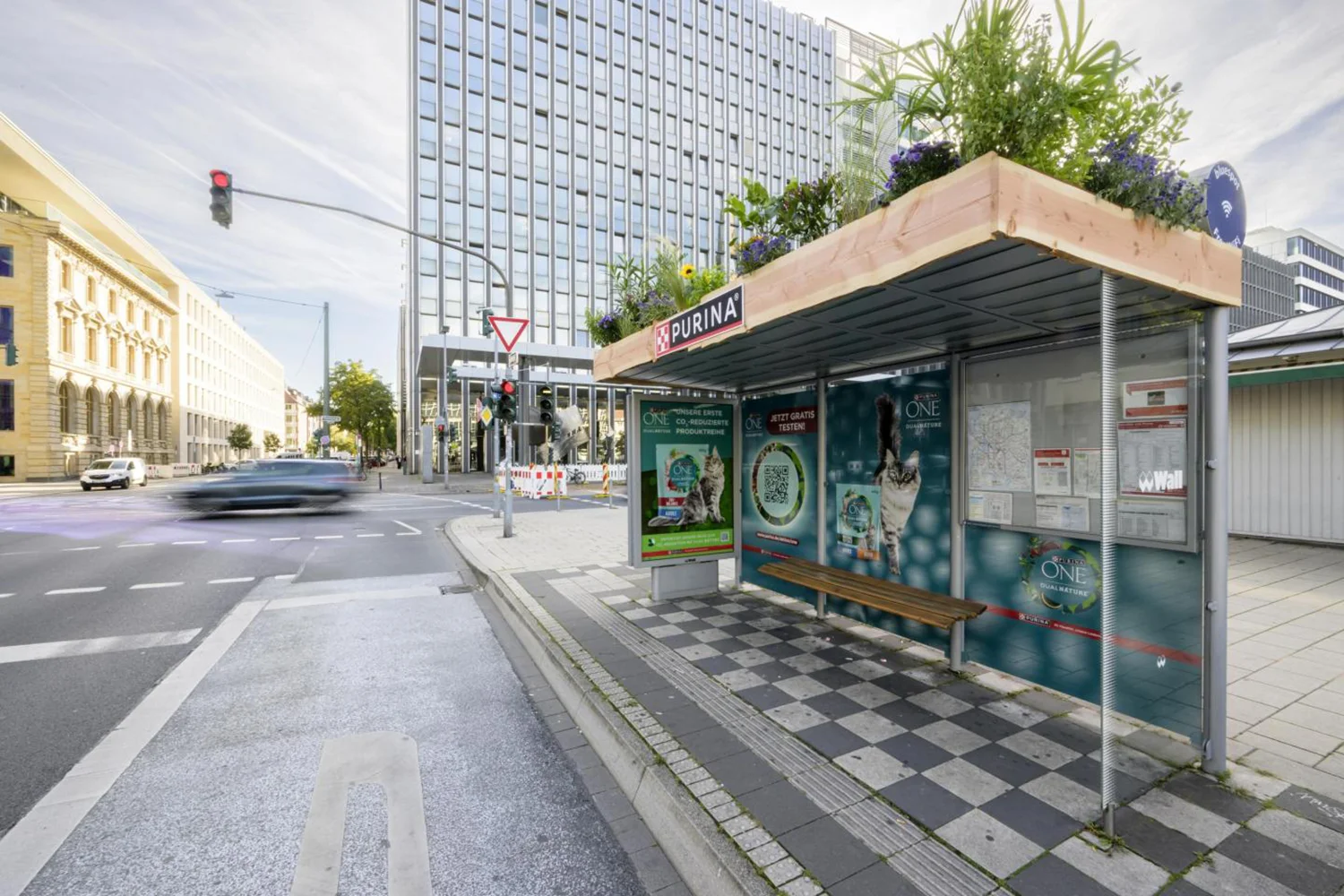 City Light Poster und vollbeklebte Bus-Wartehalle mit Gründach zeigen Werbung für Tiernahrung.