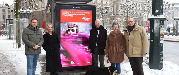 Fünf Personen und ein Hund stehen rund um ein Digital City Light Poster an einer Bus-Wartehalle am Hamburger Rathaus. Das Digital City Light Poster zeigt eine Kampagne, die auf den plötzlichen Tod durch Epilepsie aufmerksam macht.