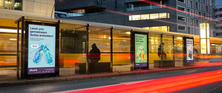 Digital City Light Poster mit Getränkewerbung an Tramhaltestelle an Rosenthaler Platz Ecke Torstraße in Berlin bei Nacht.