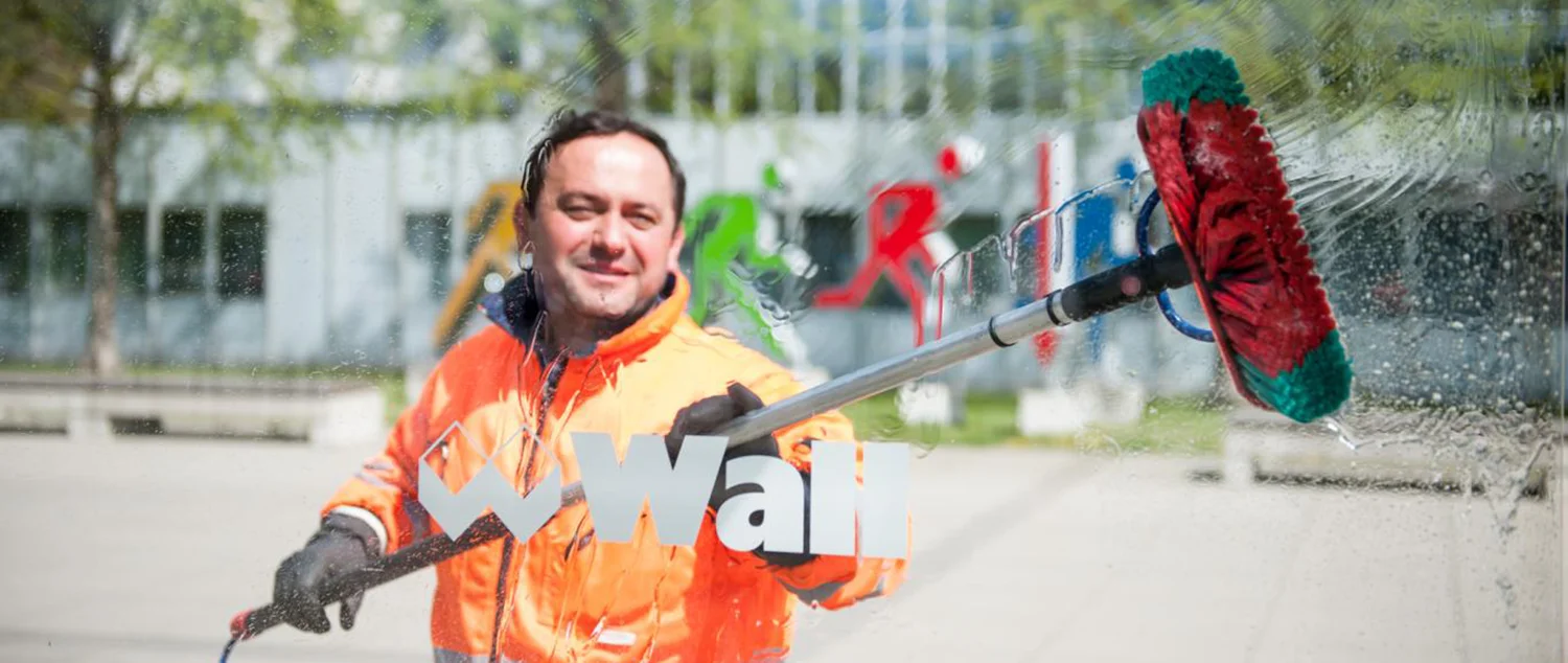 Servicemitarbeiter der Wall GmbH reinigt Wartehalle mit einer Waschbürste.