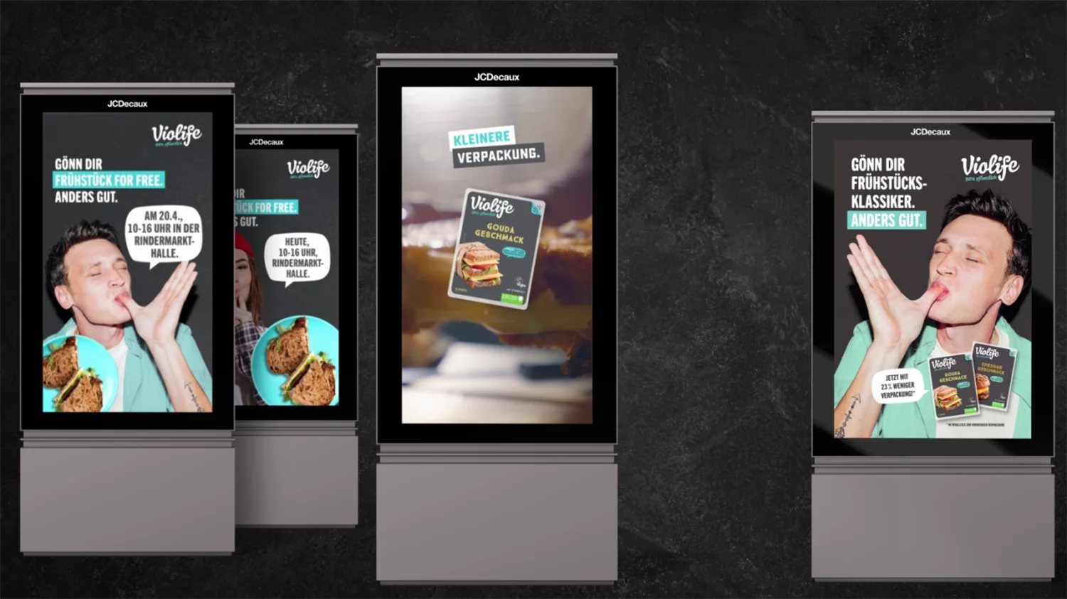 Vier Digital City Light Poster vor schwarzem Hintergrund zeigen Werbung für vegane Frühstücks-Alternative.