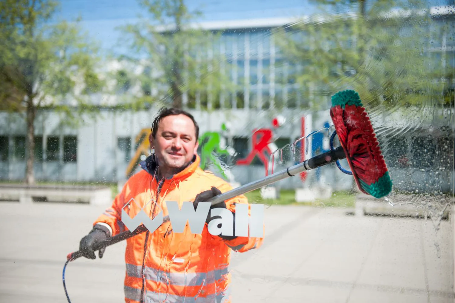 Servicemitarbeiter der Wall GmbH reinigt Wartehalle mit einer Waschbürste.