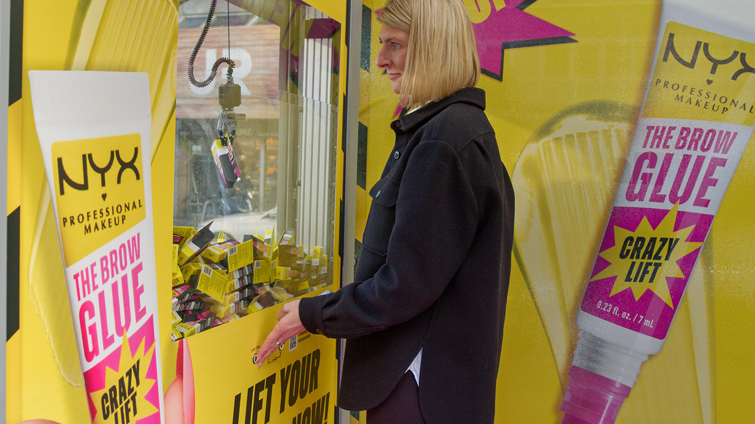 Wartehallenbranding mit Greifarmautomat zeigt in Düsseldorf Werbung einer Kosmetikmarke.