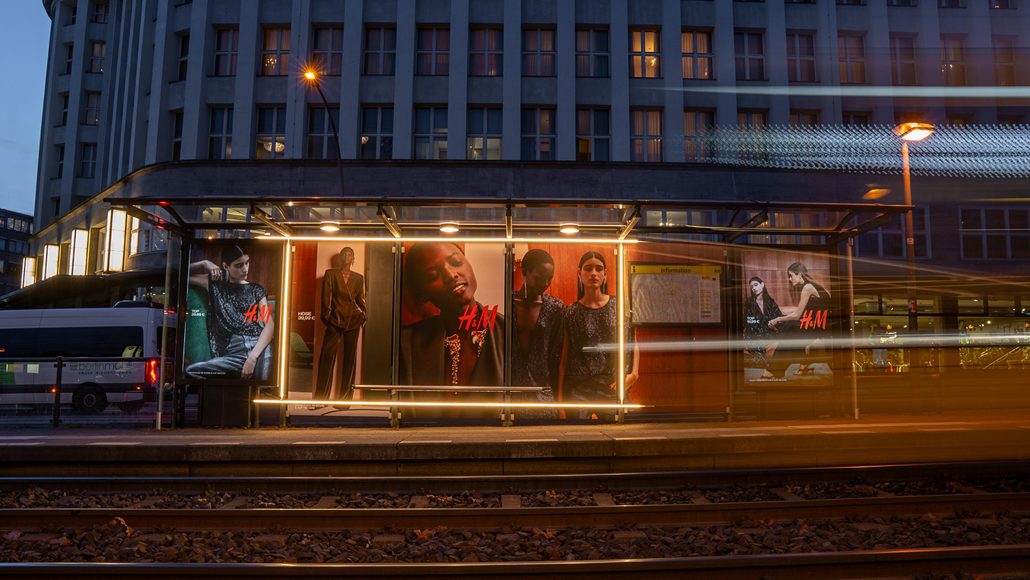 Wartehallenbranding für Modemarke mit Beleuchtung an Berliner Tramhaltestelle bei Nacht.